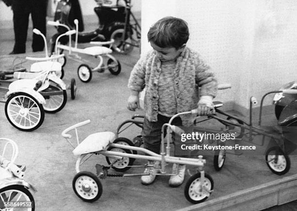 Petit garcon essant un tricycle dans un magasin quelques jours avant Noel, a Paris, France, le 21 decembre 1961.