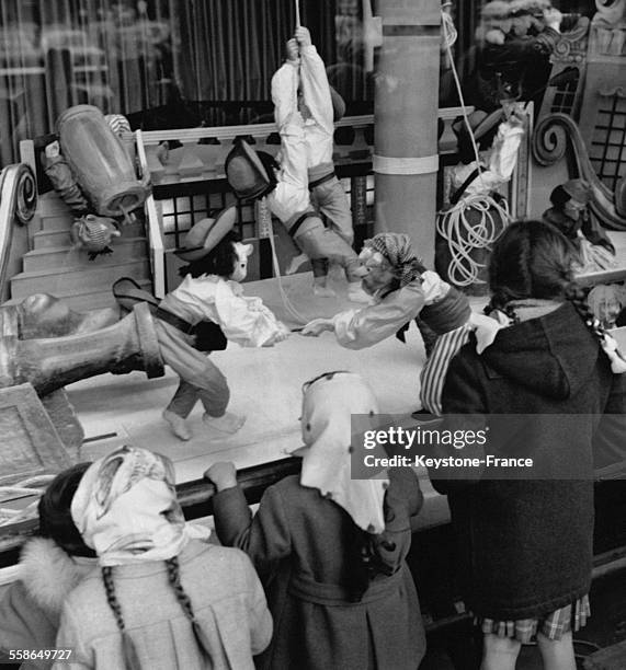 Enfants admirant une scene de bateau pirate interpretees par des automates dans une vitrine d'un grand Magasin, a Paris, France, le 13 novembre 1959.