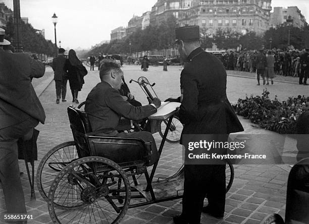 Un soldat, blessé de guerre, signe le registre près de la tombe du soldat inconnu à Paris, France le 14 juillet 1930.