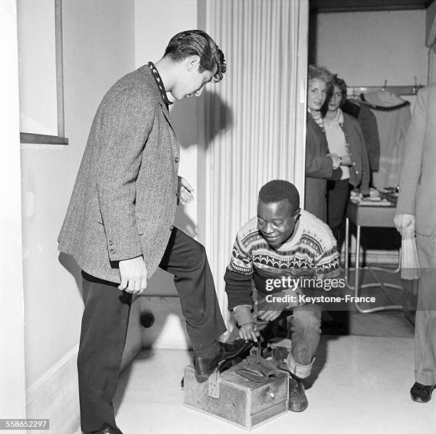 Paul Anka se faisant cirer les chaussures avant de rentrer sur la scene du theatre de l'Etoile pour un concert en 1960, a Paris, France.
