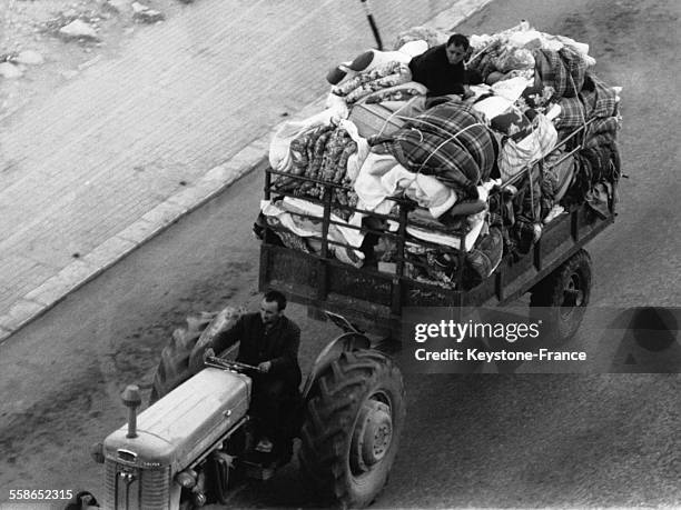 Un refugie libanais assis sur le haut d'un tas de literie, habits et autres objets personnels entasses dans une charrette, son ami au volant du...
