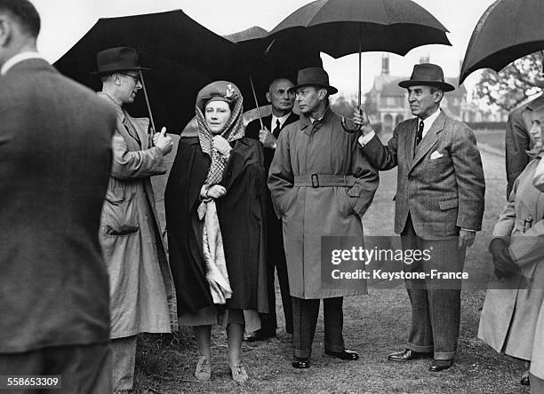 Sous une pluie diluvienne, le roi George VI et la reine Elizabeth en visite a la Ferme royale, le 18 mai 1946 a Windsor, Royaume-Uni.
