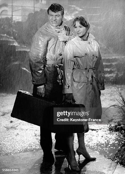 Françoise Arnoul et Henri Vidal sous des trombes d'eau dans une scène du film 'La bête à l'affût' de Pierre Chenal dans les studios à Paris, France...