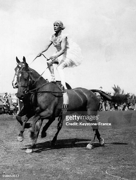 Jeune femme debout en équilibre sur deux chevaux à l'occasion d'un tournoi militaire en présence du roi, à Hounslow, Royaume-Uni, le 24 avril 1934.