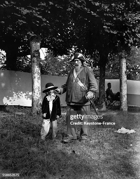 Homme déguisé en garde-champêtre avec un enfant lors du carnaval de Montfort-l'Amaury, France, circa 1930.