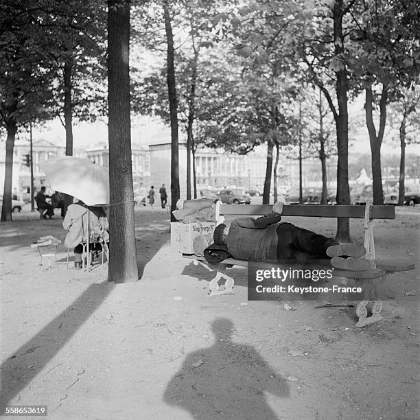Dans le jardin bordant la Place de la Concorde et l'avenue des Champs-Elysées à Paris, France, un homme se repose à l'ombre couché sur un banc et un...