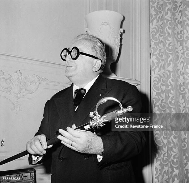 Marcel Achard et son épée d'Académicien qu'il vient de recevoir dans les salons de la Maison de l'Amérique Latine à Paris, France le 1 décembre 1959.