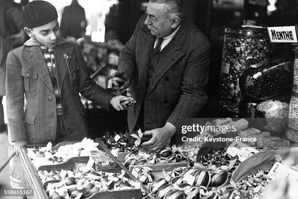 Un jeune garçon achète un oeuf de Pâques chez un confiseur, à Paris, France en 1933.