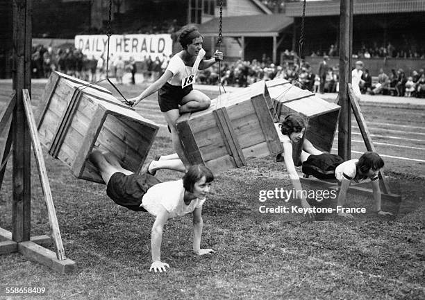 Trois concurrentes à la course à obstacle passent à travers des boites durant la course au Crystal Palace, Londres, Royaume-Uni le 14 juillet 1930.