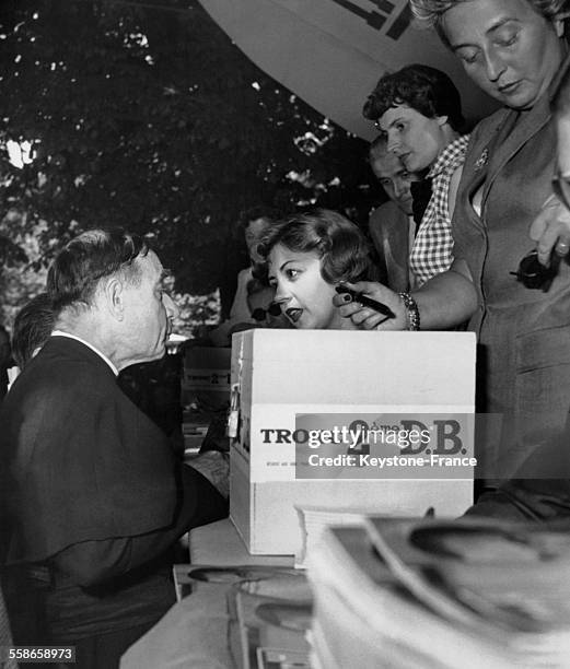 La comédienne et chanteuse Suzy Delair vend une de ses photos dédicacées à un curé de campagne lors de la kermesse aux étoiles au profit des oeuvres...