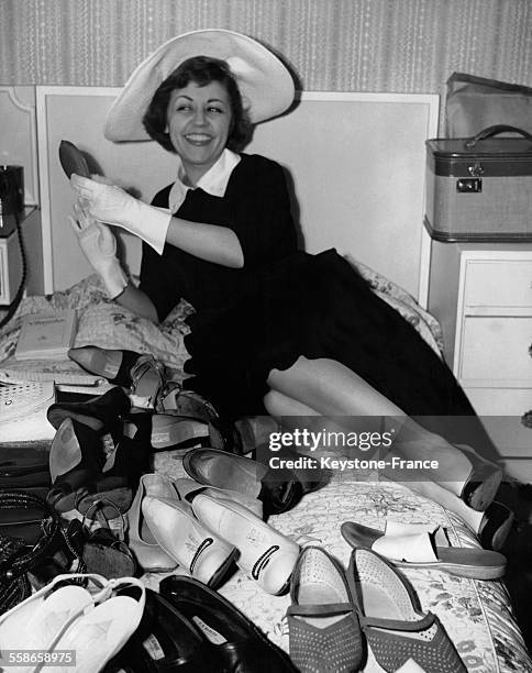 La comédienne et chanteuse de cabaret française Suzy Delair se relaxant dans son hôtel, entourée de plusieurs paires de chaussures, le 6 juin 1954, à...