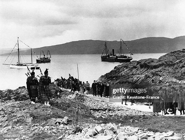 Es joueurs de cornemuse saluent le Clan Maclean qui marchent sur la jetée pour se rendre à la cérémonie des 100 ans de leur chef, sur l'Ile de Moll,...