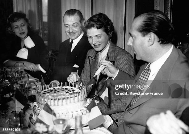 Le cinéaste italien Roberto Rosselini coupe son gâteau d'anniversaire en compagnie de son épouse Ingrid Bergman, et de leurs amis Fernand Gravey et...