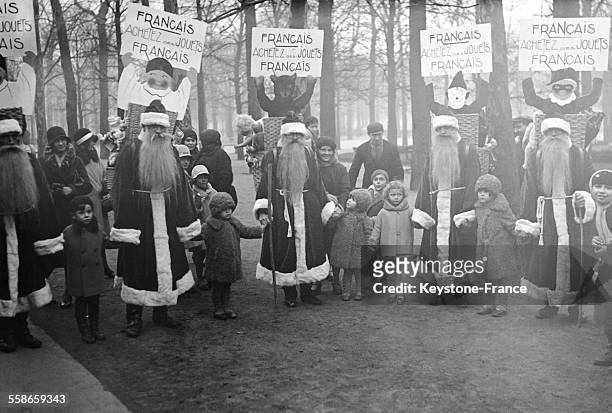 Hommes-sandwichs déguisés en Père Noël se promenant dans la rue et portant un écriteau où l'on recommande aux mamans françaises d'acheter des jouets...