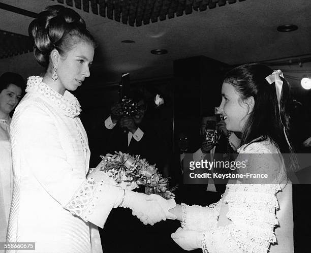 La Princesse Anne reçoit un bouquet de fleurs des mains de la fille du réalisateur de 'Run free, run wild', le film projeté en première mondiale à...