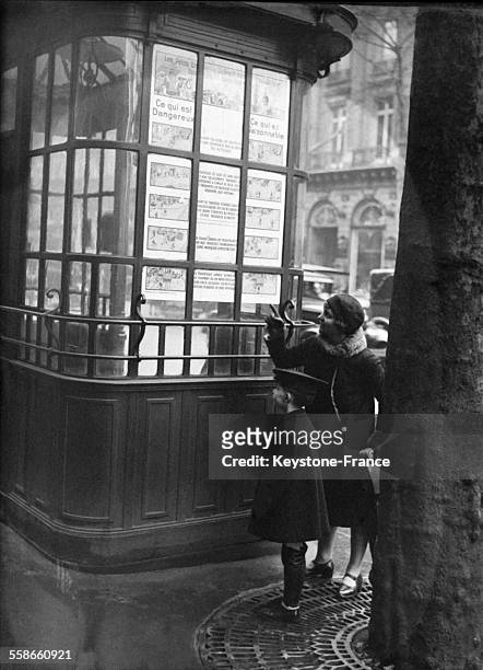 Une femme et son enfant regardant les affiches de la Société des transports en commun de Paris qui, par le dessin, enseigne aux piétons les actes et...