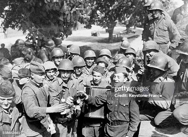 Les militaires boivent un verre de vin pour fêter la jonction des deux armées, sur un air d'accordéon, à Torgau, Allemagne, en mai 1945.
