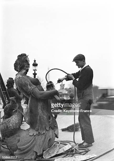 Nettoyage d'une statue en forme d'un poisson, la veille du premier avril place de la concorde le 31 mars 1931 à Paris, France.
