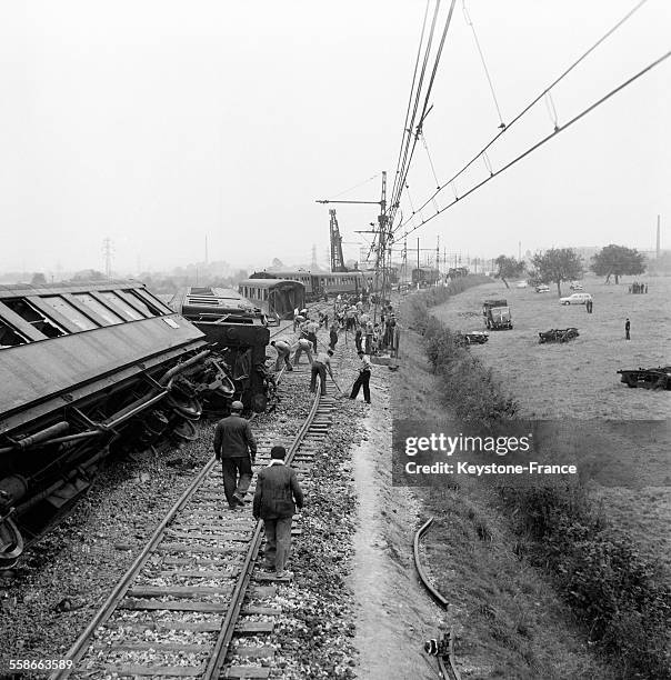 Les équipes d'ouvriers occupés à remettre les voies en état après le déraillement d'un train qui a causé la mort de cinq personnes et trente blessés,...