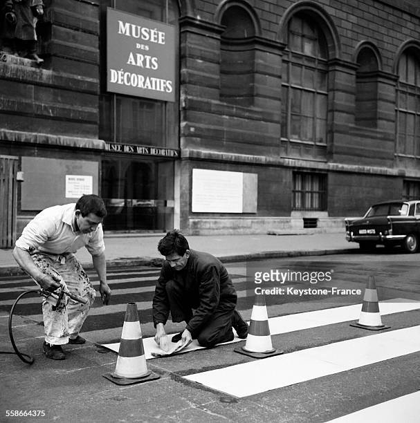 Rue de Rivoli, installation d'un nouveau passage clouté fait de bandes en matière plastique jaune fixées au sol, à Paris, France le 12 janvier 1965.