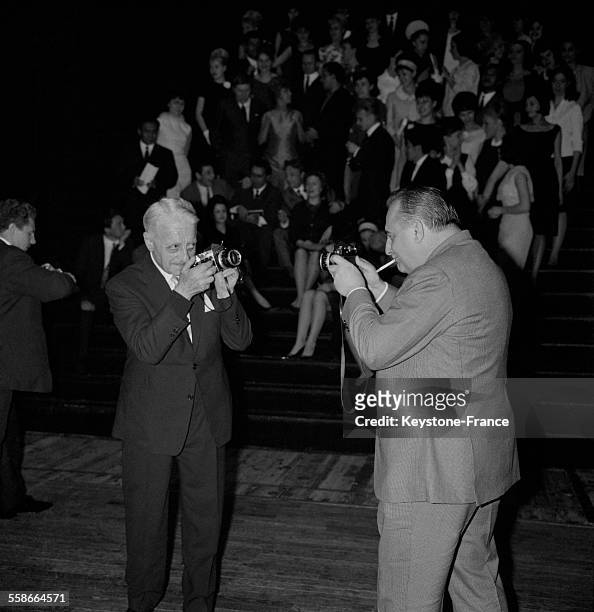 Georges Auric et Bruno Coquatrix se photographiant mutuellement lors d'une soirée à Paris, France, en 1965.