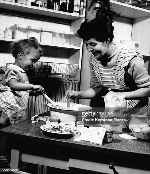 Une maman et son enfant prépare la pâte pour les biscuits de Noël, en Allemagne en décembre 1959.