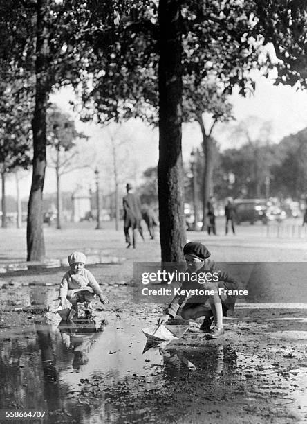 Enfants jouant dans une flaque d'eau dans un jardin à Paris, France circa 1930.