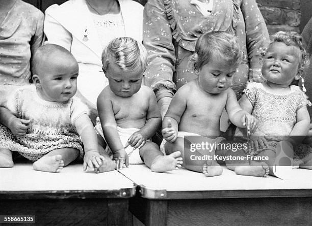 Quatre bébés assis devant leurs mères attendent le verdict du jury après avoir participé au concours du plus beau bébé organisé par le Comté d'Essex...