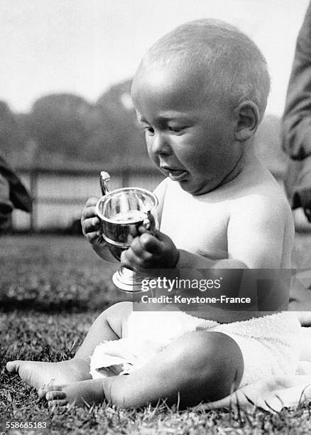 Un bébé vient de remporter le concours du plus beau bébé et étudie son trophée d'un air satisfait, le 1er juillet 1933 à Neasden, Royaume-Uni.