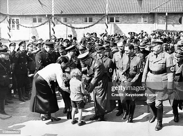 Adolf Hitler reçoit des fleurs de la part d'un petit garçon lors d'une cérémonie officielle en compagnie de dirigeants du parti nazi, le 25 avril...