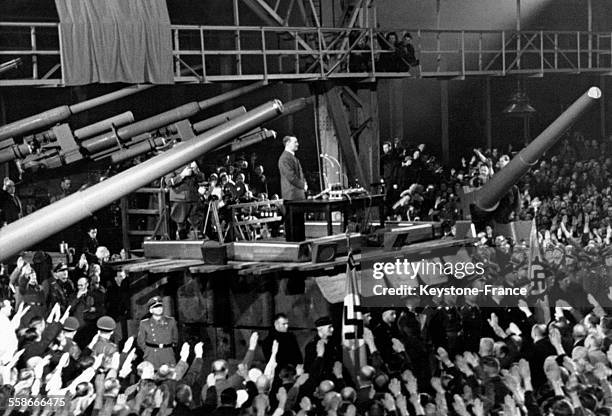 Dans une usine d'armement, Adolf Hitler prononce un discours, perché sur un tank, devant un parterre d'ouvriers effectuant le salut nazi, le 10...