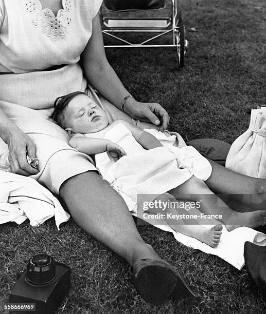 Une petite fille s'est endormie entre les jambes de sa mère, assise par terre, lors du 'Diaper Derby', ou course de bébés à Palisades Park, dans le...