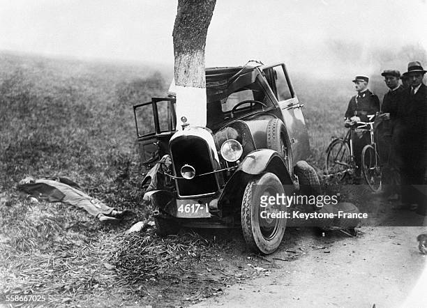 Vue de la voiture qui s'est écrasée contre l'arbre, à gauche le cadavre git au sol, près de Metz, France le 10 novembre 1931.