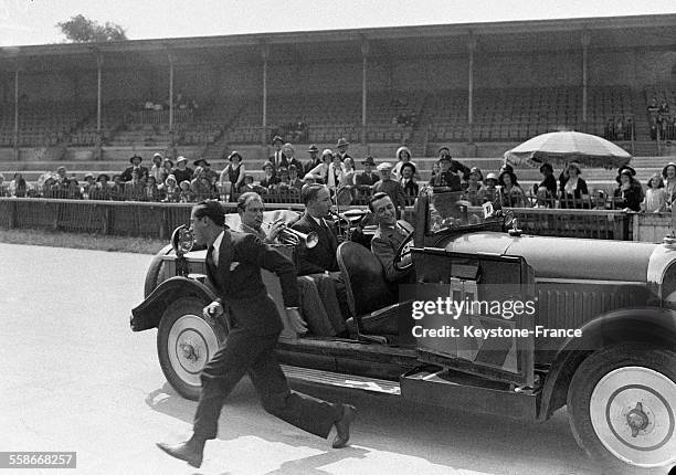 Un homme court devant une voiture occupée par un groupe de jazz à l'occasion du huitième championnat automobile des artistes au Parc des Princes, le...