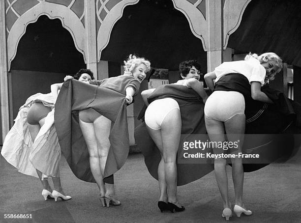 Quatre jeunes femmes soulèvent leurs jupes pour montrer leurs sous-vêtements lors du Festival au Jardin des Plaisirs de Battersea le 12 juillet 1952...