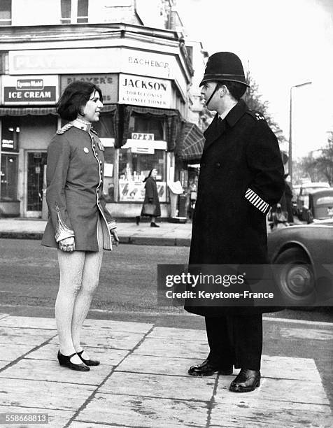 Une jeune femme vêtue d'une veste d'uniforme face à un policier britannique sur Portobello Road, circa 1950 à Londres, Royaume-Uni.