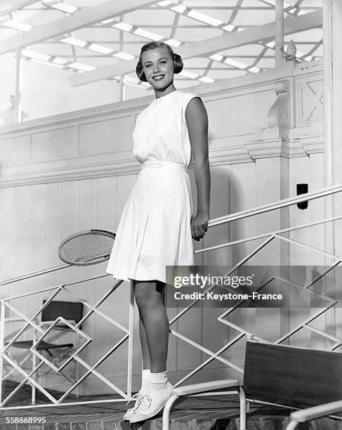 Jeune femme en tenue de tennis, portant une raquette à la main.