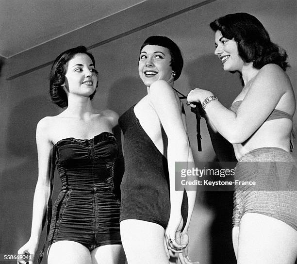 Une jeune femme réajuste le ruban de maillot de bain d'une deuxième sous l'oeil attentif d'une troisième jeune femme, avant de concourir au titre de...
