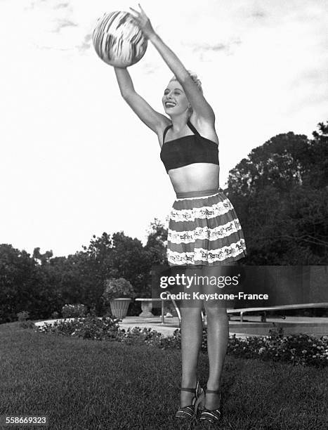 Actrice d'origine tchèque Vera Ralston joue au ballon en talons hauts sur le gazon près de sa piscine, circa 1940 en Californie.