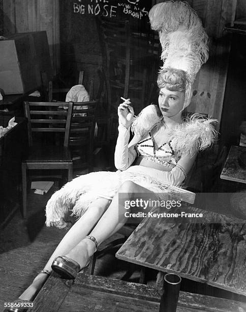 Jeane LaRue, starlette, fume une cigarette à sa sortie de scène, dans son costume de scène à plumes, à Philadelphie, PA.