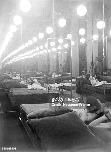 Jeunes femmes allongées dans des canapés face à un miroir dans une maison close à Paris, France, circa 1930.