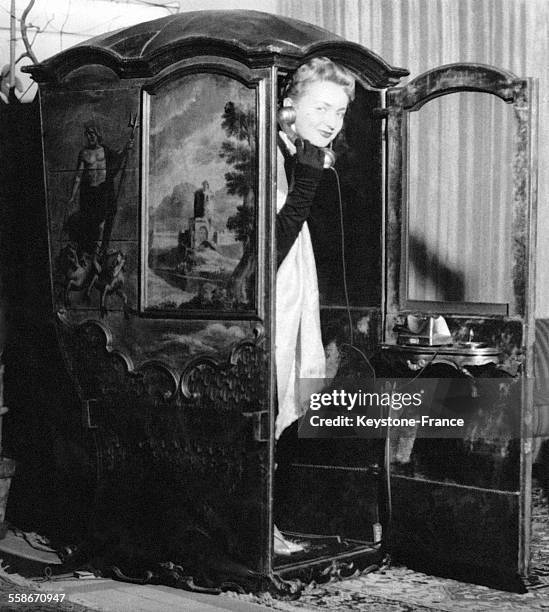 Une femme sort d'un carrosse français du dix-septième siècle transformé en cabine téléphonique dans le hall d'un hôtel, en Allemagne.