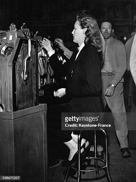 Une femme joue aux machines à sous du casino de Reno, le Harold's Club, la plus grande salle de jeux américaine pour l'époque circa 1950, à Reno, NV.
