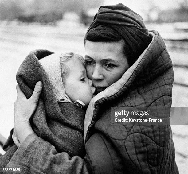 Sur le quai d'une gare, une femme tient dans ses bras son enfant en attendant un train, en Allemagne le 17 décembre 1945.