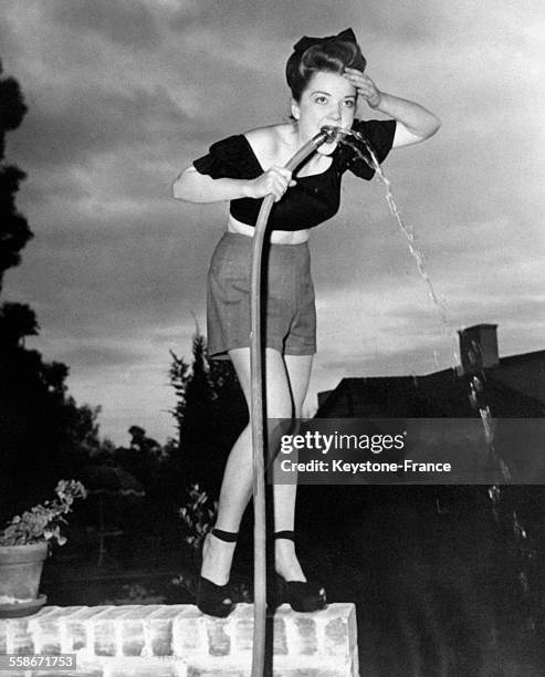 Actrice Anne Baxter boit l'eau au tuyau d'arrosage, aux Etats-Unis en 1946.