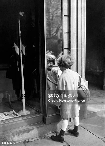 Enfant sur le chemin de l'école se regarde dans une glace, à Paris, France le 2 octobre 1931.