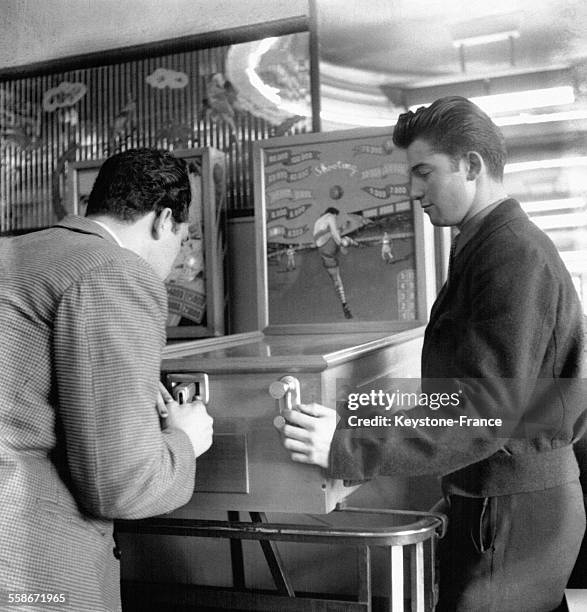 Des jeunes gens jouent au flipper dans un café, le 21 mars 1951 à Paris, France.