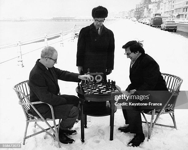 Robert Byrne et Raymond Keene s'entraînent aux échecs sous l'oeil attentif de Nikolay Krogius sur le front de mer enneigé, en prévision d'un tournoi...