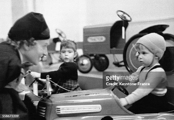 Un petit garçon s'amuse à conduire une automobilie en modèle réduit sous l'oeil attendri de sa mère dans un grand magasin le 2 décembre 1938 à New...