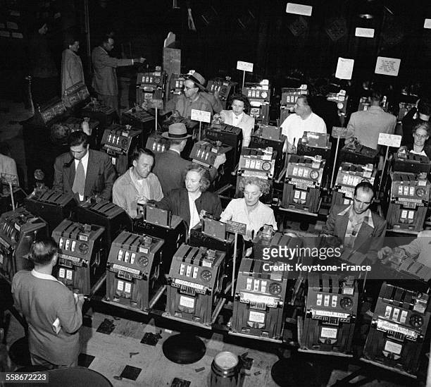 Des gens jouent aux machines à sous du casino de Reno, le Harold's Club, la plus grande salle de jeux américaine pour l'époque circa 1950, à Reno, NV.